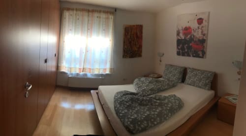 Bedroom at Giustina Apartment in Gargazzone with double bed, wooden wardrobe, window with mountain view, and wall art