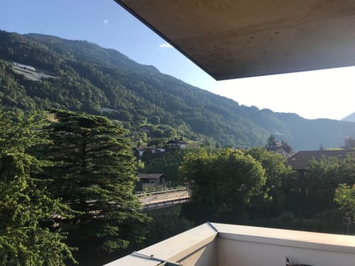 Blick vom Balkon des Apartamento Giustina über das Tal von Gargazzone mit bewaldeten Bergen und traditionellen Alpengebäuden