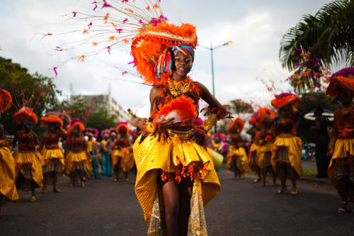 Danseuse de carnaval colorée avec coiffe orange et jupe jaune se produisant à Saint-François, Guadeloupe
