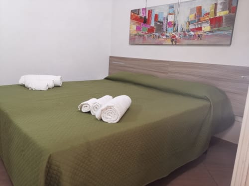Green bedspread with rolled white towels in a modern bedroom at Casa Vacanze Del Golfo, Castellammare del Golfo