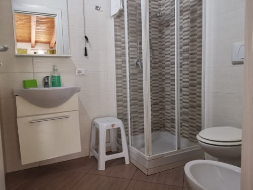 Modern bathroom in Castellammare del Golfo apartment with shower enclosure, sink, toilet, and wooden flooring