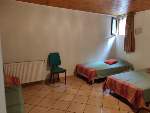 Chambre lumineuse de l'hôtel Marjori au Lauzet-Ubaye avec deux lits, plafond en bois et vue sur les montagnes