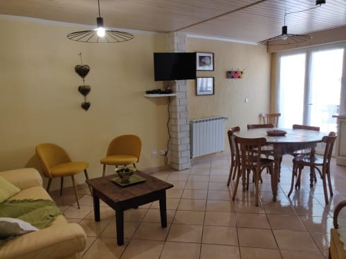 Spacieux séjour de l'hôtel Marjori avec table à manger, sièges jaunes et vue sur les montagnes au Lauzet-Ubaye