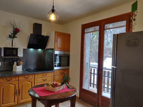 Cuisine lumineuse de l'appartement Le Lauzet-Ubaye avec meubles en bois, électroménagers modernes, table ronde et vue sur les montagnes