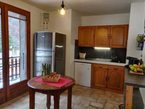 Appartement cuisine moderne à Location MarjoRI avec meubles en bois, électroménagers inox, table à manger et montagne