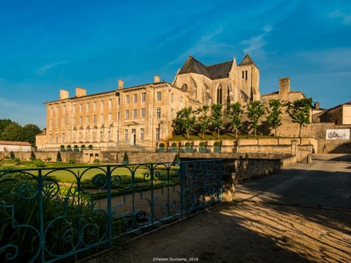 Relais Motel de Maisonnay : Manoir en pierre historique avec clocher d'église, pont en fer vert et jardins entretenus à Maisonnay