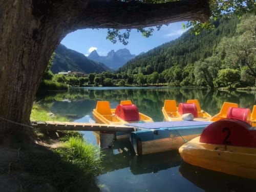 Kayaks colorés amarrés sous une grotte à l'hôtel Marjori, avec vue sur le lac alpin et les montagnes du Lauzet-Ubaye