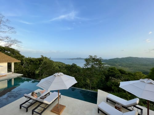Retraite yoga luxe à Paquera avec piscine à débordement, vue océan, transats et jungle verdoyante surplombant Puntarenas