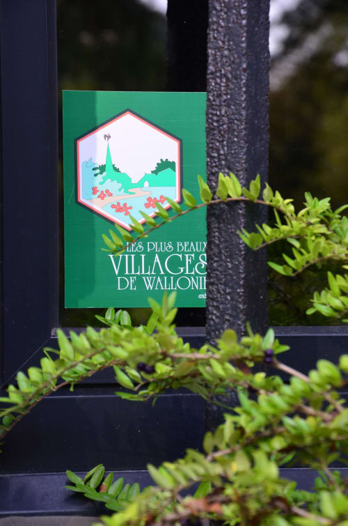 Green hexagonal sign for 'Les Plus Beaux Villages de Wallonie' displayed at Le Moulin Des Ramiers hotel in Crupet, Belgium