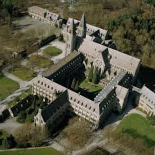 Vue aérienne de l'hôtel Le Moulin Des Ramiers à Crupet, Belgique, montrant des bâtiments en pierre à l'architecture distinctive et