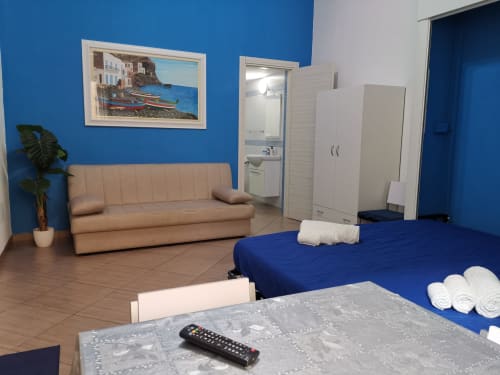 Studio Blu apartment at Casa Vacanze Del Golfo with blue walls, bed, sofa, and en-suite bathroom in Castellammare del Golfo