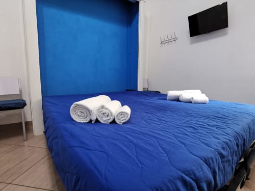 Blue bedroom in Studio Blu apartment at Casa Vacanze Del Golfo with rolled towels on bed, flat screen TV, and city views