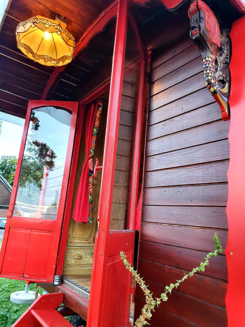 Red caravan entrance at Les Refuges Du Chalet in Jalhay with decorative lantern and wooden door