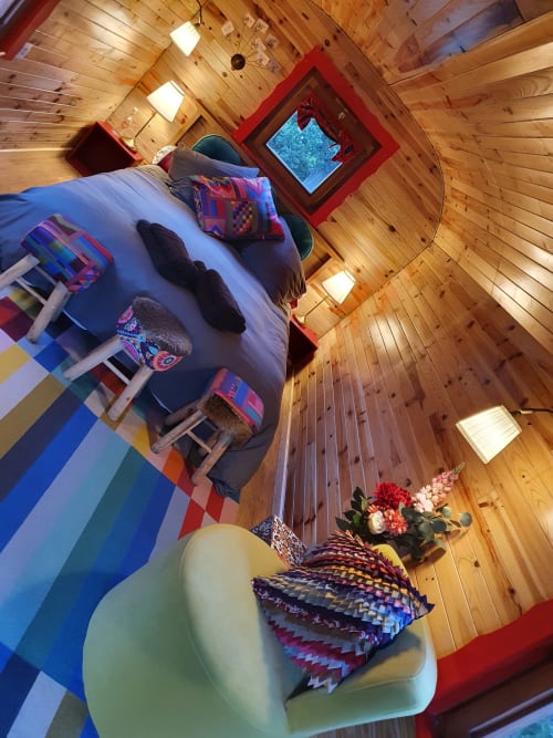 Cozy wooden cottage interior at Les Refuges Du Chalet with colorful bedding and red window frame