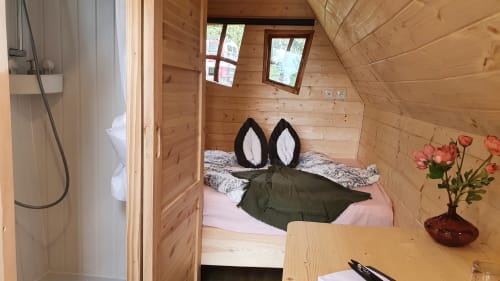 Gemütliches Holzschlafzimmer mit Doppelbett, rosafarbenen Laken und Blumen in Les Refuges Du Chalet, Jalhay