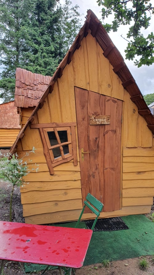 Holzhütte in den Refuges Du Chalet in Jalhay mit Spitzdach und roter Tür in Gartenanlage