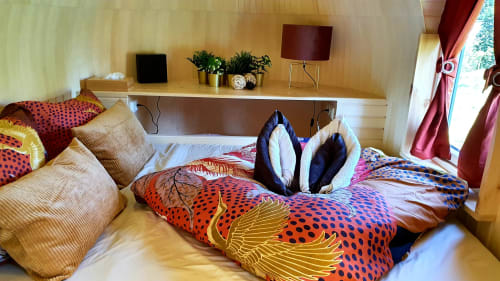Farbenfrohe Schlafzimmer im Chalet Les Refuges Du Chalet in Jalhay mit lebendigen gemusterten Bettbezügen und Holzmöbeln