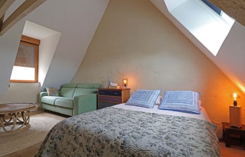 Chambre douillette sous les combles à La Dragonne B&B à Bellême avec canapé vert, lit, lucarnes et éclairage chaleureux