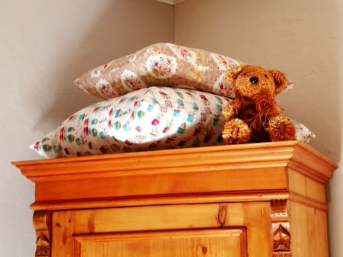 Colorful patterned pillows and teddy bear on wooden armoire, Berry Nature room at Aux Prés Du Berry