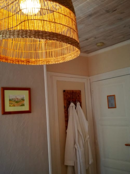 Bathroom with yellow woven pendant light, white towels, framed artwork at Aux Prés Du Berry