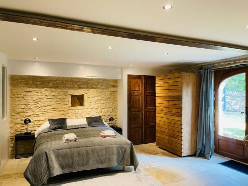 Chambre spacieuse à Vue Sur Gindou avec mur en pierre, poutres apparentes et portes donnant sur la piscine à Gindou, France