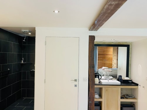 Salle de bain moderne avec douche carrelée noire, meuble vasque en bois et plafond à poutres apparentes à la maison d'hôtes Vue Sur Gindou à Gindou, France