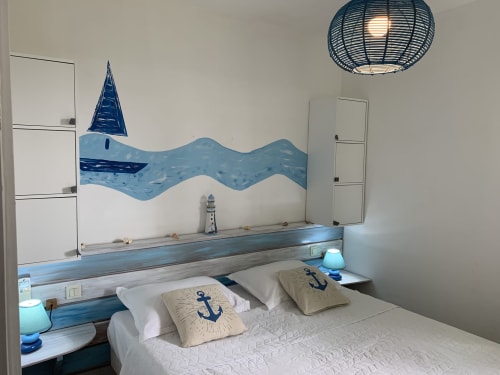 Chambre aux thèmes nautiques aux Caribluewave Apartments avec art mural voilier, coussins ancre et luminaire suspendu tressé