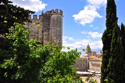 Medieval tower overlooking Gordes village with cypress trees and stone buildings in Provence, France