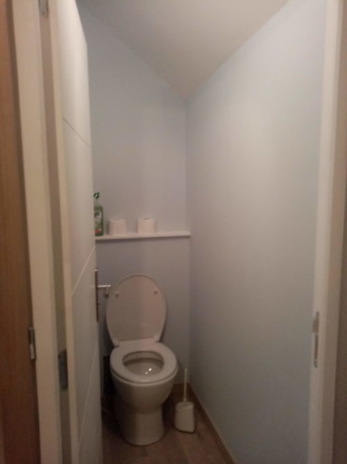 Petite salle de bain dans la chambre de l'hôtel Varette Patricia LES CLEMATITES EN COTENTIN avec toilettes blanches, étagère et miroir