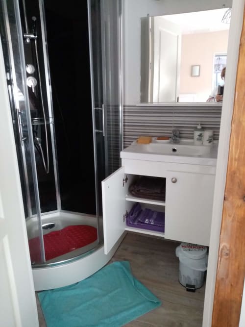 Salle de bain moderne de l'hôtel Varette Patricia avec douche, vasque blanche et dosseret aux carreaux rayés