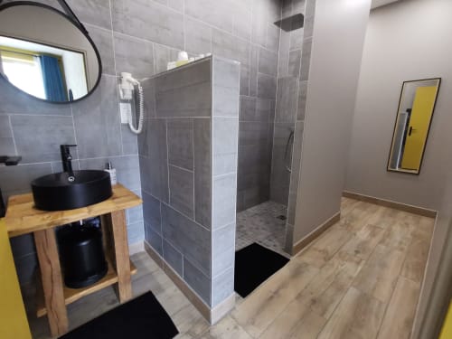 Salle de bain moderne du gîte La Cour d'Hortense avec vasque noire, douche ouverte et parquet