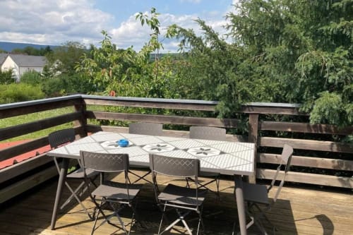 Terrasse ensoleillée du gîte Le Clos d'Azel en Alsace avec table de patio, chaises et vue sur les montagnes