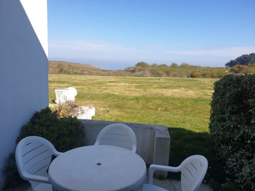 Mobilier de patio blanc surplombant un verdoyant jardin à l'appartement Locmaria Belle Ile en Mer avec vue sur mer