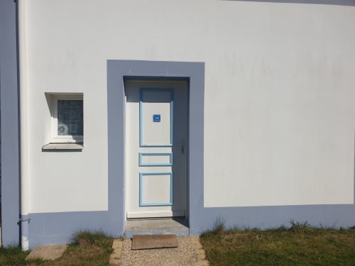 Entrée de la Résidence 34 aux Locations Loc'Maria, Belle Île en Mer, avec porte blanche bordée de bleu et plaque numérotée