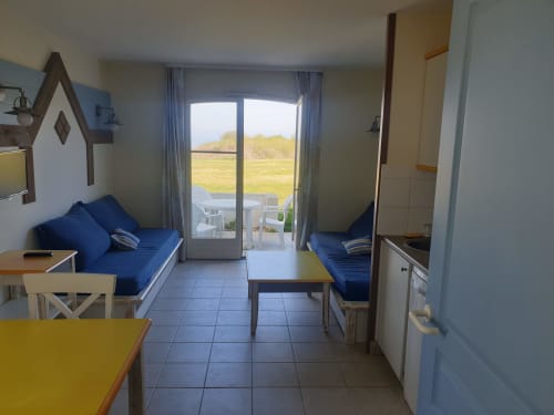 Intérieur lumineux avec salon bleu, kitchenette et terrasse vue mer à Loc'Maria, Belle Île en Mer