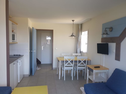 Séjour lumineux avec salle à manger, cuisine, télévision et assises bleues à Locmaria Belle Île en Mer