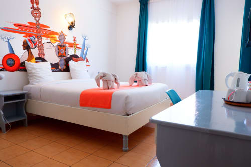 Chambre colorée à thème cirque à l'Hôtel du Cirque à Cilaos avec lit blanc, accents orange et vue sur les montagnes