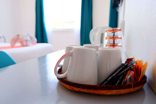 Service à thé accueillant avec tasses blanches et bâtons de vanille sur plateau orange, chambre montagne de l'Hôtel du Cirque, Cilaos
