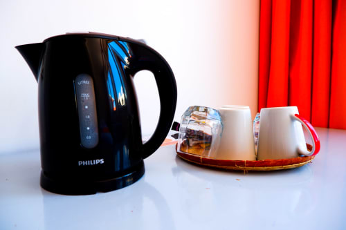 Bouilloire électrique Philips noire avec tasses blanches sur plateau rouge dans une chambre de montagne de l'Hôtel du Cirque, Cilaos