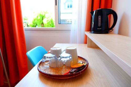 Plateau de bienvenue en chambre triple du Hôtel du Cirque avec verres, tasses, bouilloire et articles de toilette sur le bureau