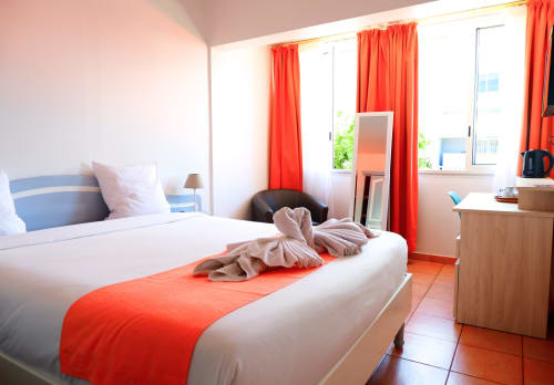 Chambre double lumineuse à l'Hôtel du Cirque à Cilaos avec accents rouges, vue sur les montagnes et équipements modernes