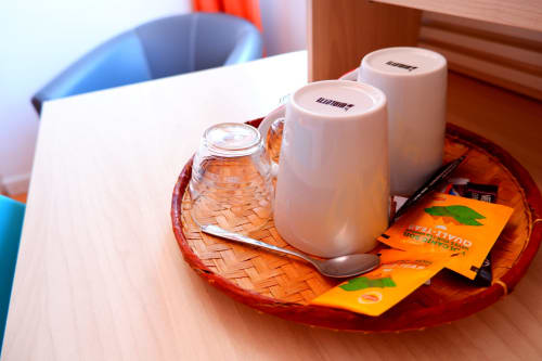 Amenités de bienvenue sur plateau rouge en chambre double de l'Hôtel du Cirque, Cilaos avec bouteille d'eau et produits de toilette
