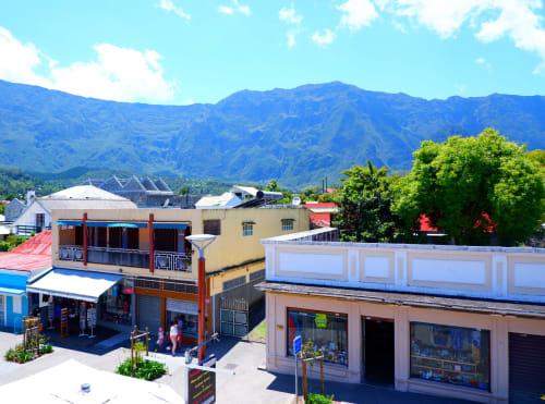 Hôtel du Cirque à Cilaos avec ses vitrines colorées et les montagnes bleues sous un ciel ensoleillé