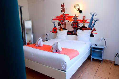 Chambre au thème du cirque aux couleurs vives à l'Hôtel du Cirque à Cilaos avec lit blanc et décoration murale rouge