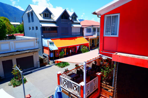 Bâtiments colorés de l'Hôtel du Cirque et cour à Cilaos avec structure rouge vif et store jaune