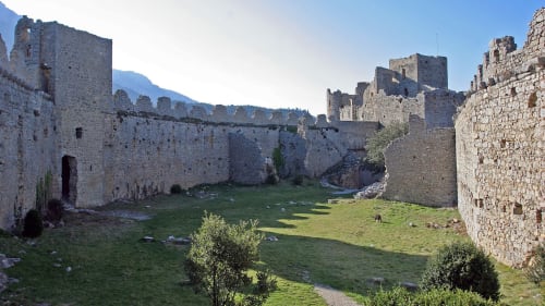 Ruines de château médiéval en pierre avec cour verdoyante et montagnes, Montséret, France - Gîte Sylvie CAMBON