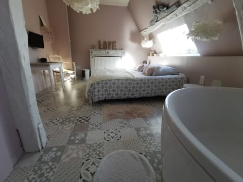 Chambre lumineuse sous les toits avec carrelage à motifs, lit, baignoire indépendante et puits de lumière à La Cour d'Hortense