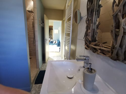 Salle de bain à La Cour d'Hortense avec lavabo blanc, miroir et sèche-serviettes électrique