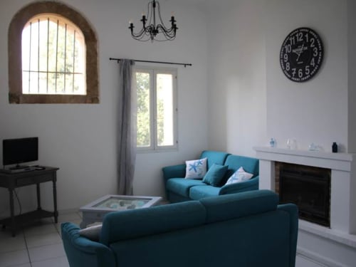 Élégant canapé bleu-vert dans le lumineux séjour de la maison d'hôtes Sylvie CAMBON à Montséret, avec cheminée et fenêtre cintrée