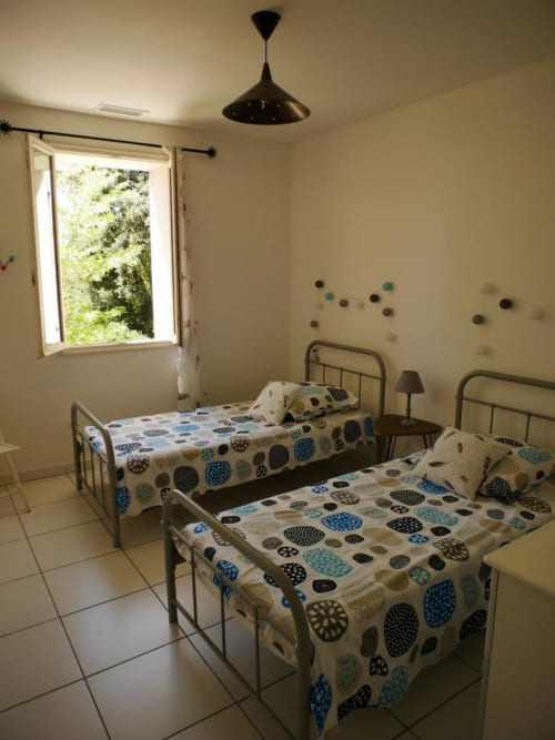 Chambre twin au gîte Sylvie CAMBON à Montséret avec lits en métal et literie à motifs